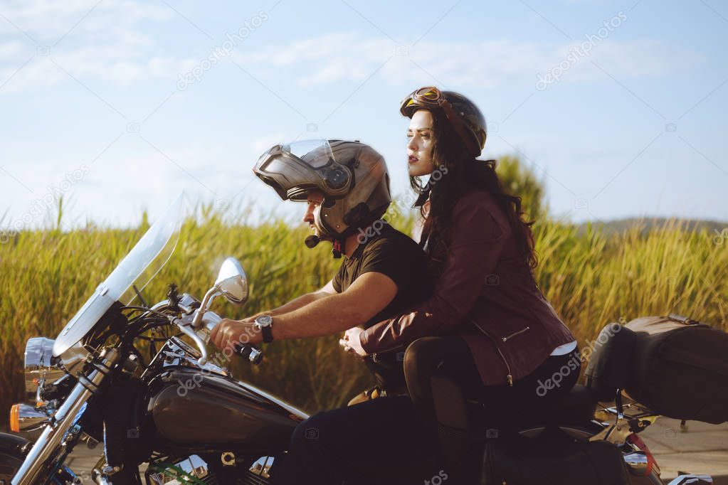 Couple on the background of the field rides a motorcycle. A man 