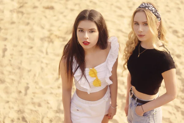 Las niñas en la playa de pie en el fondo de la arena. La morena — Foto de Stock