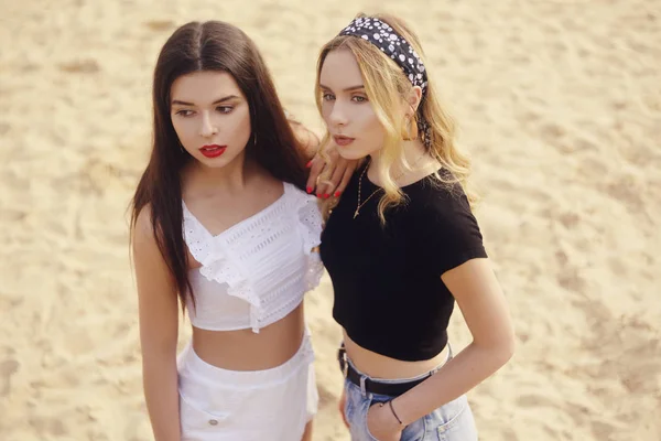 Las niñas en la playa de pie en el fondo de la arena. La morena —  Fotos de Stock