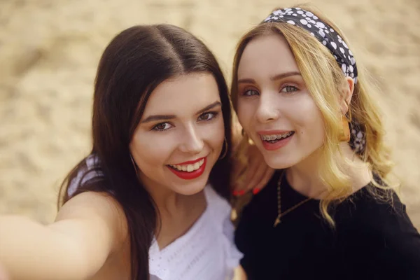 Meninas na praia estão no fundo da areia. A morena — Fotografia de Stock