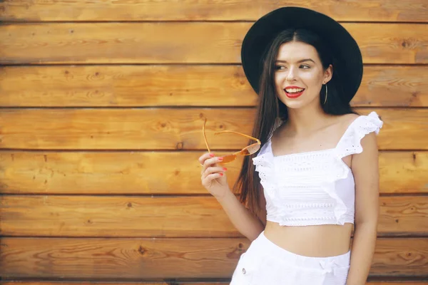 Ragazza alla moda in un cappello e occhiali. Bruna in un abito bianco — Foto Stock