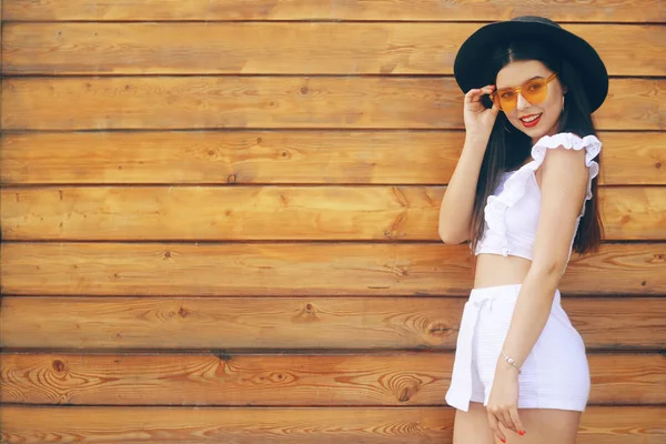 Modieus meisje in een hoed en bril. Brunette in een wit pak — Stockfoto