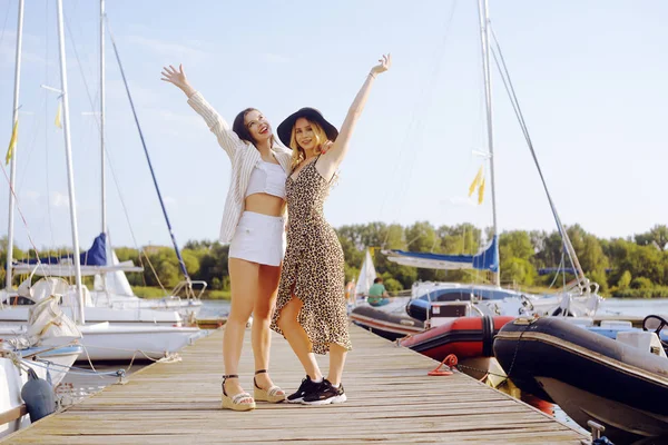 Две девушки на фоне яхт, парусные лодки улыбаются — стоковое фото