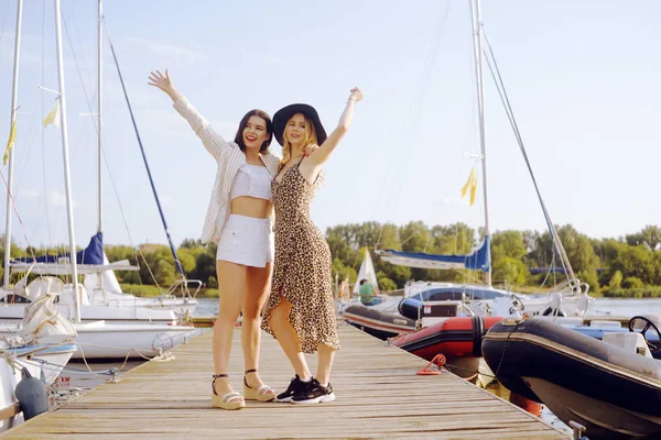 Dos chicas en el fondo de los yates, veleros sonríen — Foto de Stock