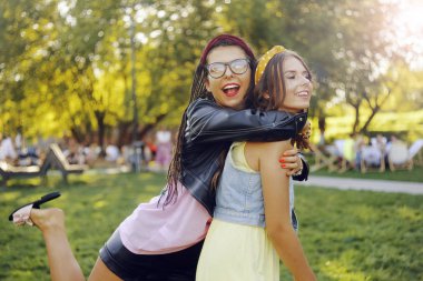 Parkta iki kız arkadaş yürüyor. Kız kardeşler eğleniyor.