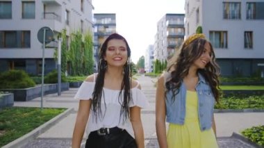 İki kız arkadaş / kız kardeş yeni binaların, ofislerin ve şehrin etrafında yürüyor. Kızlar eğlenir, yürür, güler, zıplar. Turistler yürür ve güler. Seyahat.