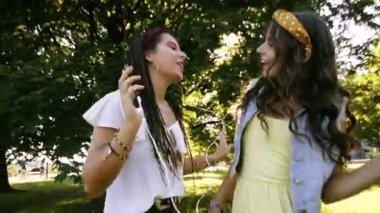 İki kız / kız kardeş çim üzerinde, kulaklık müzik dinliyor yatıyor. İki esmer parkta çimenlerin üzerinde uzanır, rahatlar, şarkı söylerler..