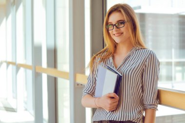 Genç sarışın kız kameraya bakıyor. Güneş gözlüklü kadın