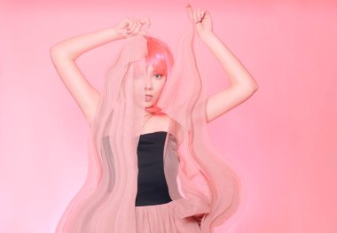 Pembe saçlı, kahverengi saçlı kız. Pembe uzun elbiseli, uçan elbiseli, kumaşlı bir manken. Pembe makyaj, tarz, moda.