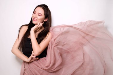 Uzun saçlı güzel esmer kız. Pembe elbiseli, uçan elbiseli, kumaşlı bir model. Pembe makyaj, tarz, moda, güzellik fotoğrafı.