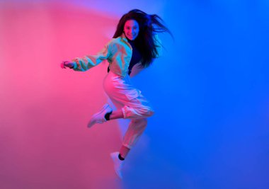 Esmer olan neon ile dans ediyor, kırmızı-mavi dansçı. Hip hop kızı, parti, gülümseme. Uçuşta model, atlama.