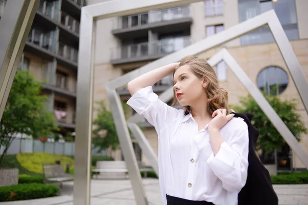 マネージャー 不動産屋 建物のポーズの背景に白いシャツの少女 短い髪の美しいブロンド モデルはレッドリップとブラックジャケット — ストック写真