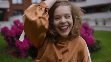 Ahşap, yeşillik ve ladin arka planında güzel bir model. Kısa saçlı ve kahverengi elbiseli bir kız. Sarışın bir ağaçta yatıyor, model modaya uygun poz veriyor. Doğada aşk