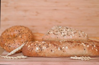 Farklı ekmek türleri, fırında taze hamur işleri. Susamlı ekmek, mısır gevreği, tohum. Farklı formlar ve rulo çeşitleri. Tahtada buğday kulakları. Metin veya logo için yer, indirimler