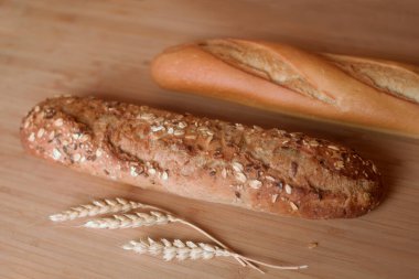 Farklı ekmek türleri, fırında taze hamur işleri. Susamlı ekmek, mısır gevreği, tohum. Farklı formlar ve rulo çeşitleri. Tahtada buğday kulakları