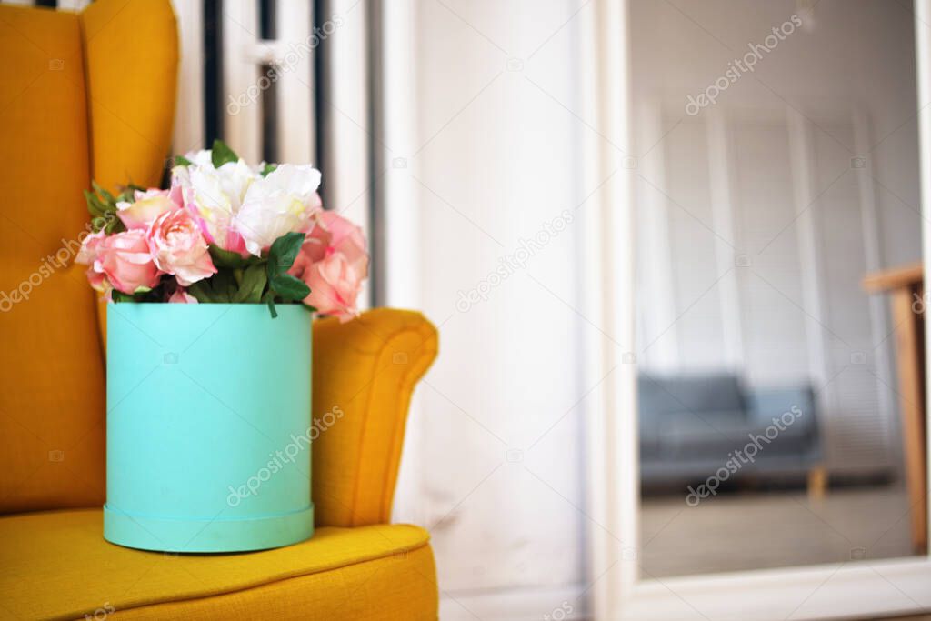 Beautiful flowers, peonies in a box of turquoise color. The bouquet is on the armchair