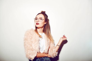 Pembe pelerinli beyaz arka planda bir kız, şık bir saç stili olan esmer bir kadının görüş gözlüğü. Güzel saçlı genç bir kızın moda fotoğrafı. Kotlu model