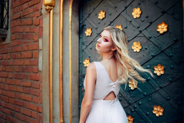 The princess enters her room in the castle. A gorgeous blonde on the background of the door looks into the distance. Girl with gorgeous makeup