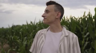 Bir adam mısır tarlasında yürüyor ve tarladaki yapraklara dokunuyor. Çiftlik işçisi, arazi sahibi. Adam mısırların nasıl olgunlaştığını kontrol ediyor, gülümsüyor..
