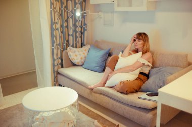 Kız akşamları evde TV 'nin önündeki kanepede oturur. Yorgun bir kadın işten sonra haberleri izler..