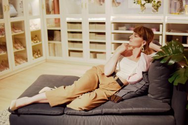 Kız dolabının arka planında kanepeye uzanmış kıyafetlerle. Soyunma odasında bir kadın. Şık bir kadın ne giyeceğini düşünür, moda ipuçları..