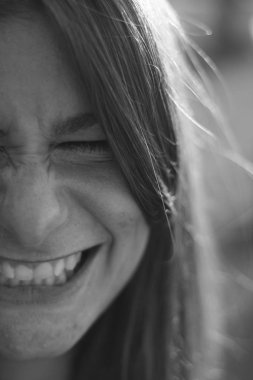 Genç kadın portre siyah ve beyaz. İle sıkı gülümseyen dişler ve gözler kapalı. 