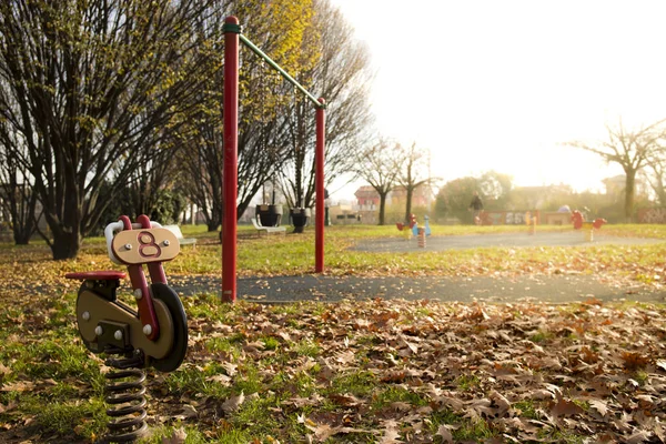 背景と黄金フレア光側のスイングと 秋に公園遊び場で赤いバイク春ライダー Copyspace の背景 — ストック写真