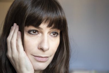 35 yaşında kadın yakın çekim portre. Beyaz uzun kumral ve patlama ile. Gülümseyen, sakin ifade, yüzünde bir el ile bakıyor.