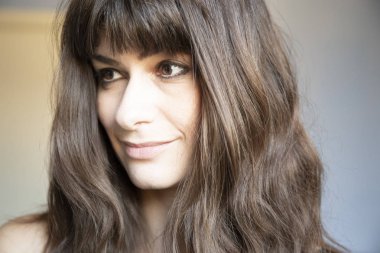 Genç kadın üç çeyrek yakın çekim portre. Beyaz uzun kumral ve patlama ile. Gülümseyen ifade, aşağı bakıyor.