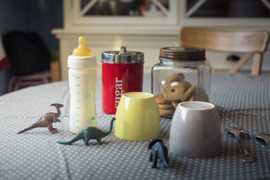 Kahvaltı hazır tablo ile cups ve dinozor ile besleme şişe bir çocuğun varlığı açığa oyuncaklar ayarla.