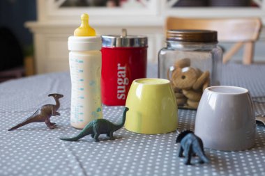 Kahvaltı hazır tablo ile cups ve dinozor ile besleme şişe bir çocuğun varlığı açığa oyuncaklar ayarla.