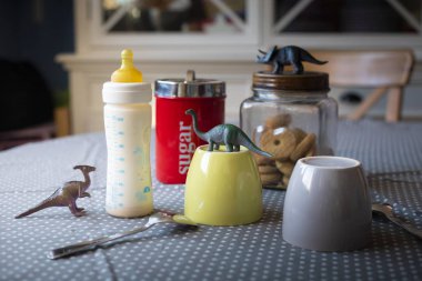 Kahvaltı hazır tablo ile cups ve dinozor ile besleme şişe bir çocuğun varlığı açığa oyuncaklar ayarla.
