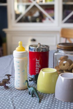 Kahvaltı hazır tablo ile cups ve dinozor ile besleme şişe bir çocuğun varlığı açığa oyuncaklar ayarlayın. Dikey vurdu.
