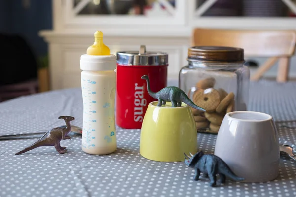 Kahvaltı hazır tablo ile cups ve dinozor ile besleme şişe bir çocuğun varlığı açığa oyuncaklar ayarla.