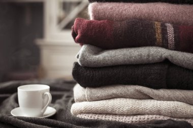 Yan, arka plan kopya alanı, rahat hygge duvar kağıdı ile sıcak içecek beyaz Kupası ile renkli kazak yığını. Doygunluğu azaltılmış vintage sesleri.