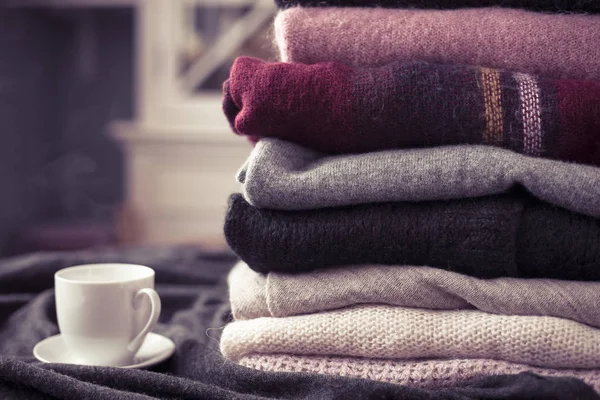 Yan, arka plan kopya alanı, rahat hygge duvar kağıdı ile sıcak içecek beyaz Kupası ile renkli kazak yığını. Pembe filtre.