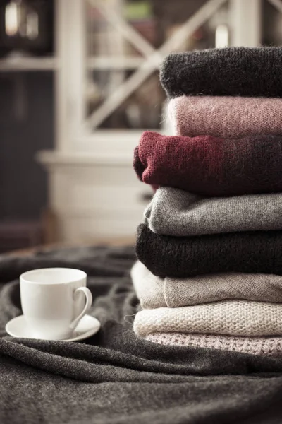 Yan, arka plan kopya alanı, rahat hygge duvar kağıdı ile sıcak içecek beyaz Kupası ile renkli kazak yığını.