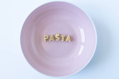Pembe bir tabak içinde gerçek makarna harflerle kelime 