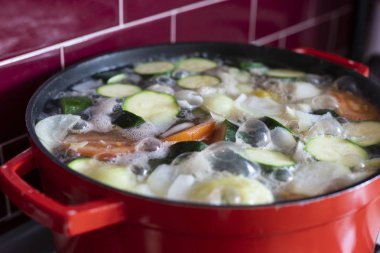 Sebze çorbası kaynar ile kırmızı pot. Köpük ve kabarcıklar ile yakın çekim. Yan görünüm.