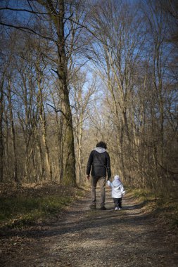 Baba ve bebek kırsal yolda yürüyor.