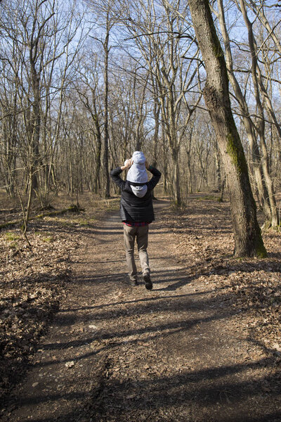 Dad carrying his baby on his shoulders in forest
