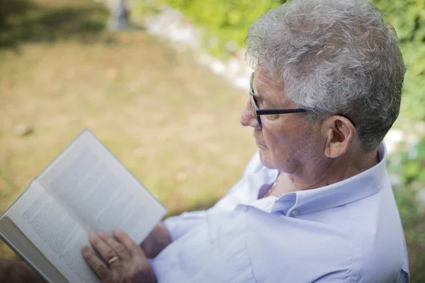 older man reading outside