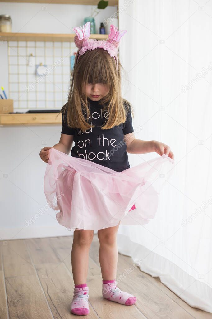 Little child girl, at home playing in disguise wearing a ballerina costume with pink tulle tutu, socks and antennas
