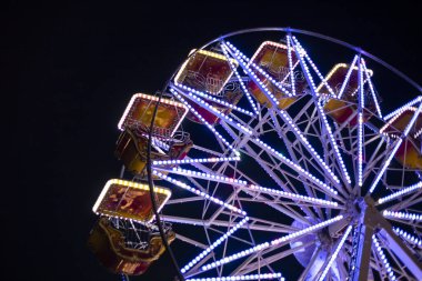 Mavi neon ışıklarla aydınlatılmış renkli dönme dolap. Rosolina Mare lunaparkı, Veneto, İtalya.