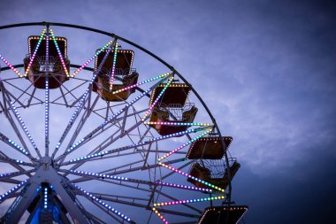 Alacakaranlıkta renkli dönme dolap, neon ışıklarla aydınlatılmış. Kopya alanı olan bir arkaplan. Rosolina Mare lunaparkı, Veneto, İtalya.