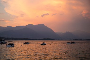 Garda Gölü 'nde pembe buğulu ve durgun tekneli inanılmaz kızıl gün batımı. Manerba del Garda, Lombardy, İtalya.