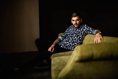 Genç yakışıklı adam kanepede poz