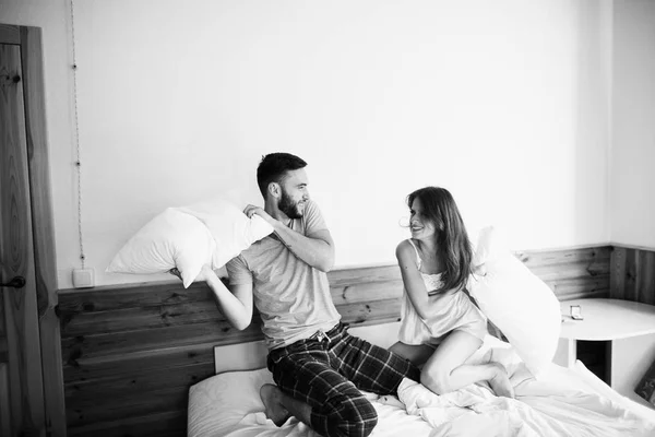 年轻夫妇在床上有枕头打架的早晨 — 图库照片