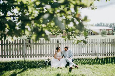 Çitin yanında oturan genç yeni evli mutlu çift 