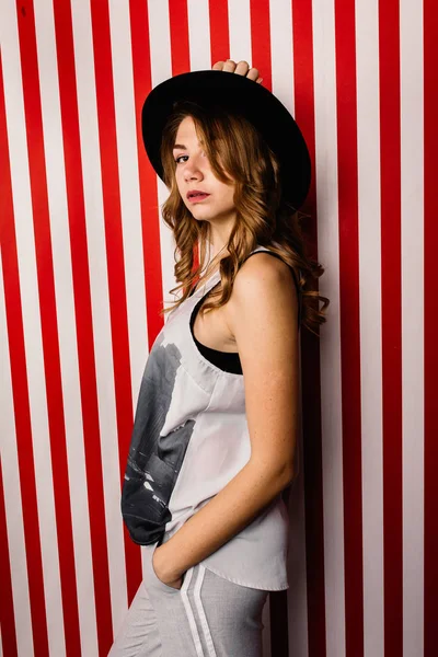 Stüdyoda poz veren şapkalı güzel bir kadın.